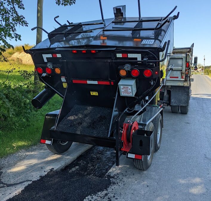 A Falcon hot box hard at work repairing asphalt potholes on a city street.