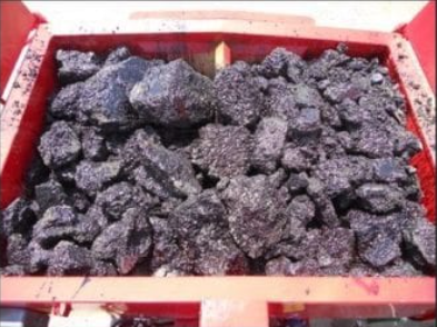 Asphalt chunks are added to a hot box to recycle them.
